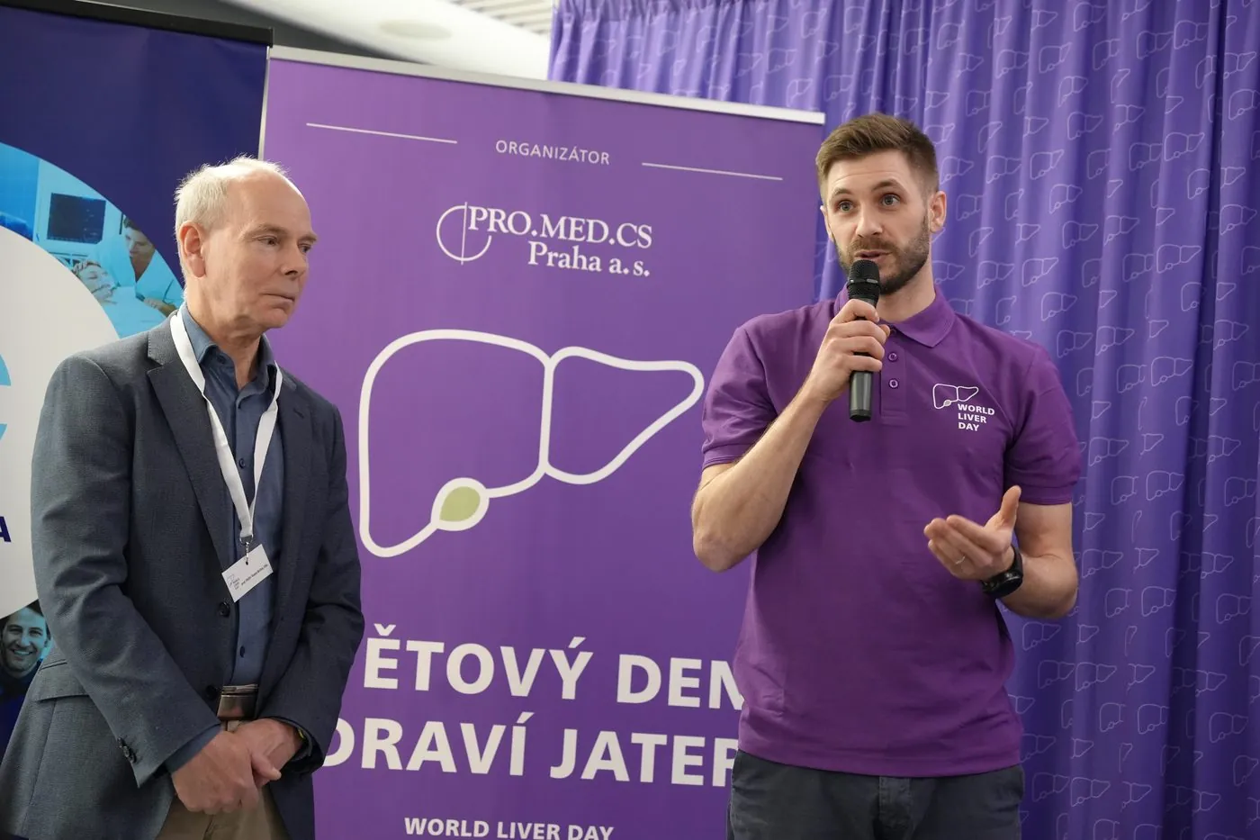 Moderátor s mikrofonem na akci ke Světovému dni jater